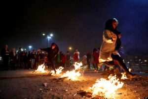 Two Iranian women jump over bonfires in the Pardisan Park in Tehran, Iran, Tuesday, March 18, 2014, during Chaharshanbe Souri, or Wednesday Feast, an ancient Festival of Fire, on the eve of the last Wednesday of the year, when Iranians jump over burning bonfires and throw firecrackers celebrating arrival of the spring which coincides with their new year, or Nowruz, which begins on March 21. (AP Photo/Ebrahim Noroozi) چهارشنبه سوری و شادی زینان در آتش بازی .