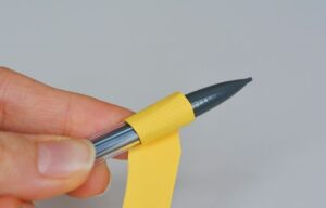 مرحله سوم و رول کردن کاغذ دور مداد یا خودکار برای شکل گیری گلبرگ های گل مقوایی یا کاغذی